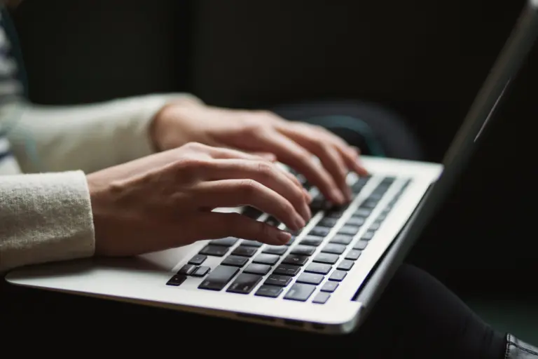 Hands typing a story on a laptop